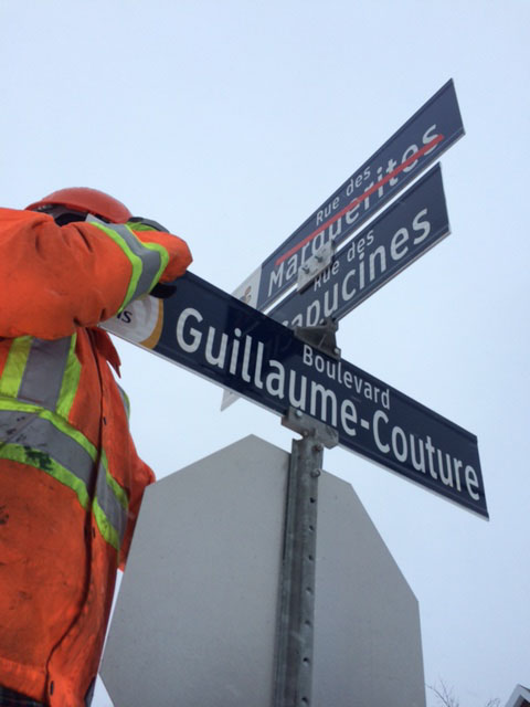 name-signTechnicien en équipement de sécurité procédant à l'installation de panneaux de noms de rues, dont le boulevard Guillaume-Couture